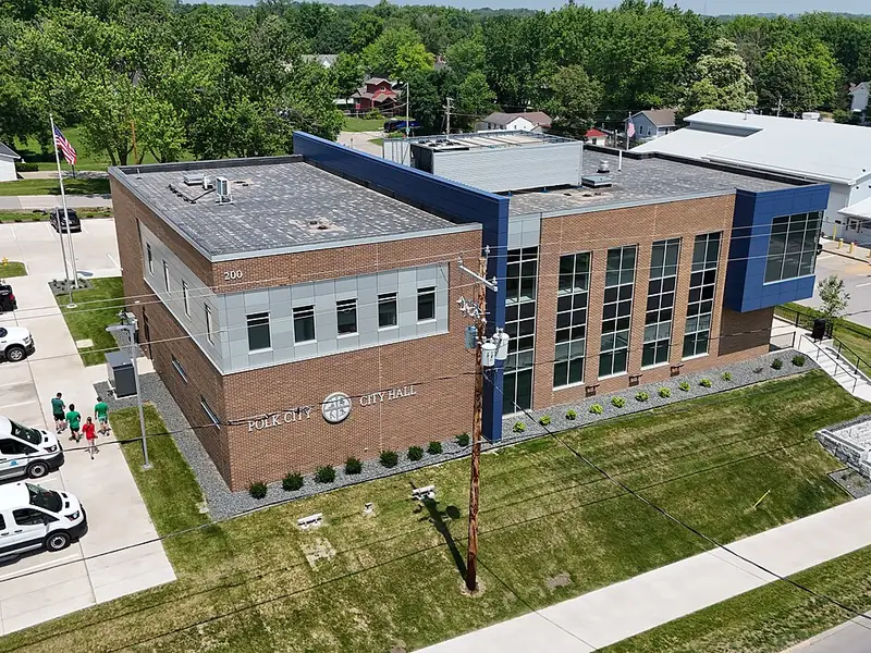 Aerial view of the brick and glass Polk City City Hall with a parking lot and lawns