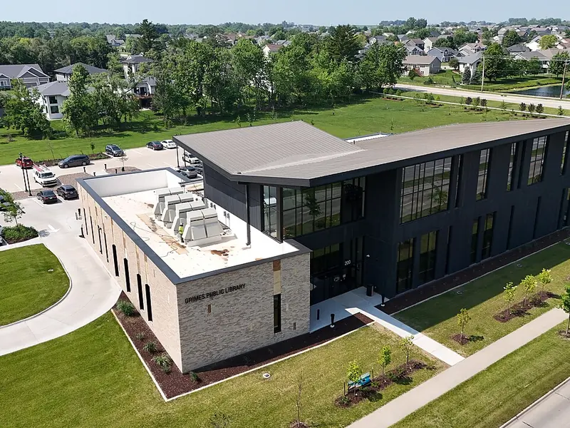 Aerial view of the modern Grimes public library building with a parking lot and green lawns